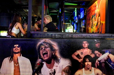 A bar, decorated with pictures of rock stars, in a club.