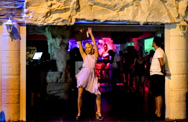 An usher dances at the entrance of a club.