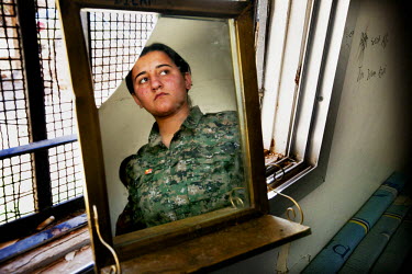 A female soldier, from the YPJ (Women's Protection Unit), looking through the window of her bedroom. The YPJ is a Kurdish female militia fighting the Islamic State and Jabhat al-Nusra in the primarily...
