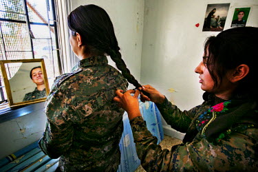 Two female soldiers plait their hair in a bedroom at the YPJ's (Women's Protection Unit) base compound. The YPJ is a Kurdish female militia that is fighting against ISIS in the primarily-Kurdish north...