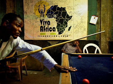 A man sleeps beneath a 'Felabration 2010' poster while a game of pool takes place at the New Afrikan Shrine, the late Fela Kuti's nightclub and now his son Femi's.