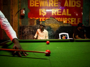 Two men sitting by a pool table as a game takes place at the New Afrikan Shrine, the late Fela Kuti's nightclub and now his son Femi's.