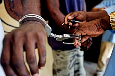 Two convicted poachers are handcuffed after interrogation at the jail in Oyem. Elephant poaching brings much needed income that, for some, outweighs the risk of a three year jail sentence.