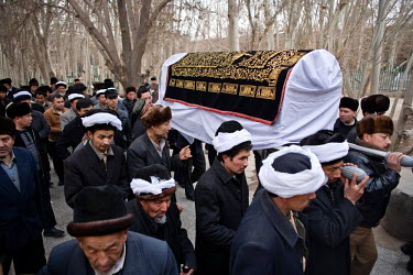 Men carrying a coffin at a Uyghur funeral at the Ikah Mosque. White cloth bound around the hats is a symbol of mourning.