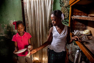 Viviane (11, left) helping her sister, Islande (13) do the dishes in their host family’s house. The sisters, both 'restaveks', have lived in servitude since 2008, when their mother gave them away. '...