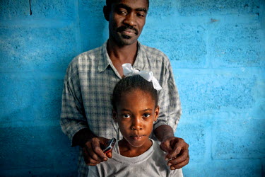 John (40) with his 'restavek' girl Mamaika (8), who has been serving for him since the earthquake of 2010. 'Restaveks' are children whose impoverished parents have indentured them into domestic labour...