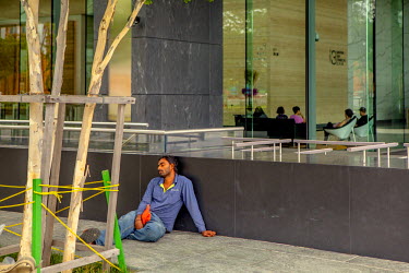 A labourer rests outside a luxury hotel.