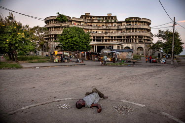 A drunk man lies on the ground in front of the former Grand Hotel building. Once a luxury destination for the wealthy and the continent's biggest hotel, the building is now a concrete shell and home t...