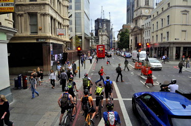 A view along Broadgate in the City of London from a London public bus with cyclists waiting for a green light.