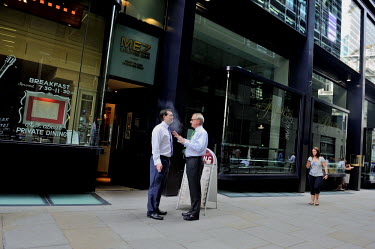 Smokers outside a restaurant on Threadneedle Walk in the City of London in discussion.