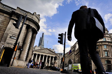 A businessman crossing the road at Bank Junction in the City of London with The Bank of England to the left and the Royal Exchange ahead.