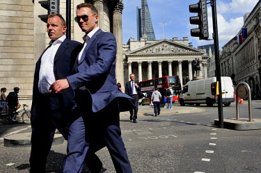 Businessmen crossing the road at Bank Junction in the City of London with The Bank of England to the left and the Royal Exchange ahead.
