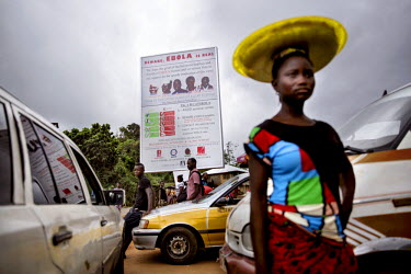 A woman walks past parked cars and a large billboard honours the local doctors, including national hero Doctor Sheik Umar Khan, who have died in the fight against ebola.