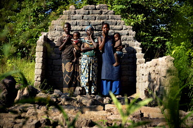Mwilambo (in the middle), widow and mother of eight children, stands in front of the remains of her burned out house with Georgine and Gilbertine, two women she is hosting, along with their 14 childre...