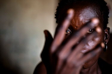 Dominique (not her real name) holds her hand in front of her face in the small room where she is taking shelter with a local host family. Dominique was raped in August 2014 but was unable to seek medi...