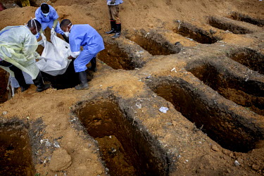 A burial team, at the King Tom cemetery, lower the body of a person who is suspected to have died from ebola into one of a group of pre-dug graves. Due to the rapid increase in burials the cemetery is...