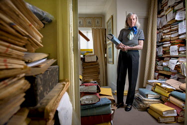 Edda Tasiemka surrounded by newspapers and cuttings that form part of her newspaper 'cutting' library for journalists, in her North London home.