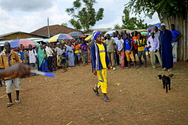 A crowd of villagers watch as a man with the symptoms of Ebola is directed to sit on a bench in main square of Dandano village. The chief of the village, Siba Koevogui, had ordered the crowd to 'Bring...