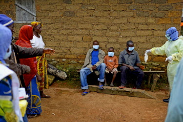 A Red Cross worker gives rubber gloves to three patients with ebola symptoms before they are transfered to Macenta for treatment. Prior to this negotiated visit by the Red Cross the villagers had deni...