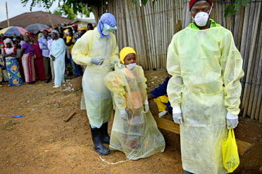 A Red Cross worker, dressed in full PPE (personal protection equipment), helps Pauline Sakou, one of a group of people with Ebola symptoms, put on barrier clothing. The sick villagers made themselves...
