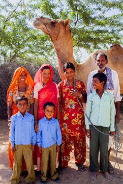Nitu and Suki (centre) (not their real names), with their family and camel in Jhaju village. Nitu now 18, was married off at the age of 10 to a boy of around the same age, but only went to live with h...