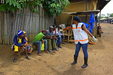 A Red Cross worker gives water to a group of people with Ebola symptoms who have made themselves known to visiting medical staff after the chief of the Dandano village, Siba Koevogui, ordered the inha...