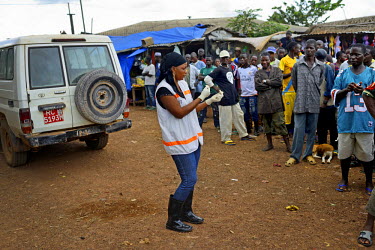 A Red Cross worker talks to villagers in the main square of Dandano soon after the chief of the village, Siba Koevogui, ordered them to 'Bring out your sick!...Don’t hide them!' The village, isolate...