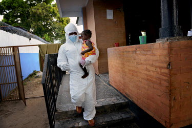 A special caretaker in dressed in full Personal Protection Equipment (PPE) carries 15 month old Mary to an ambulance for transfer to the Ebola Treatment Unit after she developed a high fever. Phoebe (...