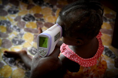 A care worker takes 15 month old Mary's temperature. She was found to have a high temperature and was transferred to the Ebola Treatment Unit.  Phoebe (6) and Mary (15 months) are two girls from Taylo...
