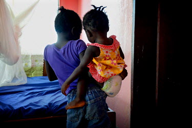 SIx year old Phoebe carries her sister Mary, 15 mths, at the ICC (interim care centre) in Monrovia.  Phoebe (6) and Mary (15 months) are two girls from Taylor Town in Bomi County who grew up together....