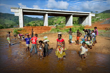 People washing clothes near a bridge whose construction has been halted. The Ebola crisis has caused construction companies, many of whom are foreign, to postpone work on major infrastructure projects...