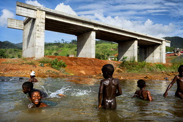 Children swim in a river near a bridge whose construction has been halted. The Ebola crisis has caused construction companies, many of whom are foreign, to postpone work on major infrastructure projec...