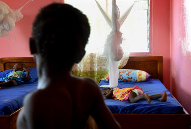 SIx year old Phoebe looks at her sister Mary, 15 mths, who is sleeping on her bed in the ICC (interim care centre) in Monrovia. Phoebe (6) and Mary (15 months) are two girls from Taylor Town in Bomi C...