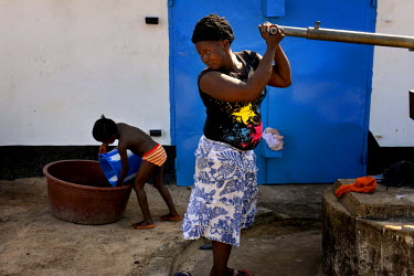 Six year old Phoebe plays with water as an Ebola survivor pumps more water for her to play with at the ICC (interim care centre) in Monrovia. Phoebe (6) and Mary (15 months) are two girls from Taylor...