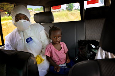 15 month old Mary and her sister (not pictured) travel with a medical worker (in personal protection equipment) to the ICC (interim care centre) in Monrovia. Phoebe (6) and Mary (15 months) are two gi...
