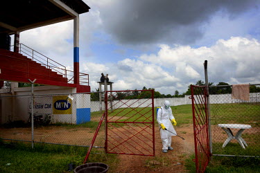 A man, dressed in full personal protection equipment (PPE) sprays a decontaminate at the football stadium where uninfected people may have been in contact with others infected with ebola. Phoebe (6) a...