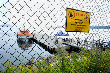 A warning sign on a chain link fence at a jetty in Nynashamn. Each summer day boatloads of day trippers arrive here to visit the Swedish capital Stockholm. Stockholm itself is too small a port to allo...