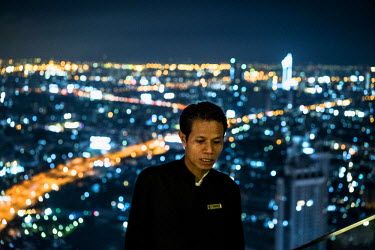A security guard on top of the Lebua State Towers in Bangkok.  ~<i>This is Bangkok</i> Globalised and localised.  Everyone is plugged into something. Cosplay from Japan. Pop from Korea. Products from...