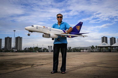 A man stands with his self-built Thai Airways replica plane in an abandoned lot on the outskirts of Bangkok.  ~<i>This is Bangkok</i> Globalised and localised.  Everyone is plugged into something. Cos...