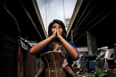 A woman carries her child along the train tracks running through the shanty homes in the Klong Toei slum. Klong Toei is a large slum in Bangkok and houses a combination of drug addicts and day laboure...