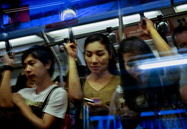 Commuters on the Skytrain in Bangkok. ~<i>This is Bangkok</i> Globalised and localised.  Everyone is plugged into something. Cosplay from Japan. Pop from Korea. Products from China. Tourists from Aust...