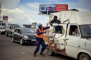 A traffic policeman has an altercation with a passenger in a van who is half hanging out of the side door of the vehicle.