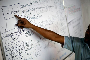 A male employee of Women's Tech points at a chart on a whiteboard at the offices of the company in Kinshasa. Women's Tech, a small enterprise started by Therese Kirongozi, a local entrepreneur, manufa...