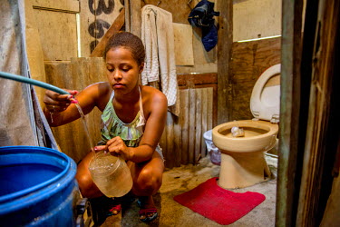 Lorena Ferreira Costa, 16, inside the bathroom at her mother's shack. Lorena has just moved to a nearby borrowed shack in Morro dos Mineiros hill, which is part of the Alemao Complex of favelas. She i...