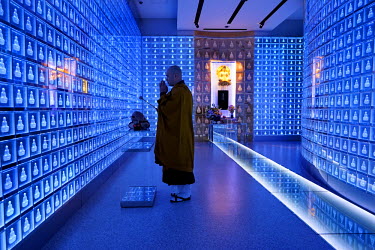 A monk prays at the Banshoji temple where, on the 3rd floor, there is a room called the Suishoden. In this hall, blue LEDs illuminate 2,000 small glass cinerariums, each containing a box holding the a...