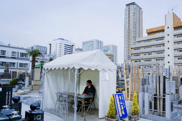 A man waits for customers at the Aoyama cemetery where grave sites can cost more than USD 100,000. The Aoyama cemetery is managed by the Tokyo Metropolitan Government. It is a large ( 263,564 m2), par...