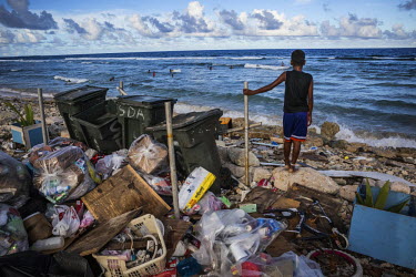 A boy stands on a rock in a rubbish dump and watches his friends play in the water. Although Ebeye's residents make a lot of efforts to keep their island clean, due the luck of regular collections, wa...