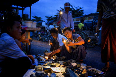 Burmese dealers use torches to inspect the quality Jade at the Mandalay Jade market.