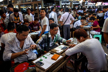 Jade dealers inspect jade at the small stone, cut, jade section of the Jade Market in Mandalay.