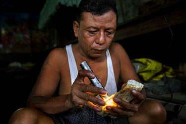 U Thein Lwin, 59, a jade dealer with over 30 years experience uses a torch to show the translucency of a special piece of high quality jade he recently acquired from Hpakant and is trying to sell in M...